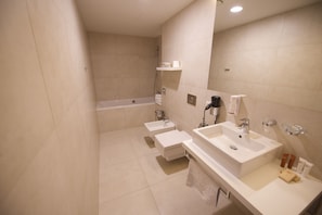 Une salle de bain moderne avec deux lavabos, une baignoire et un grand miroir.