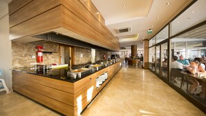 A modern buffet setup with a long counter, multiple food stations, and a fire extinguisher.