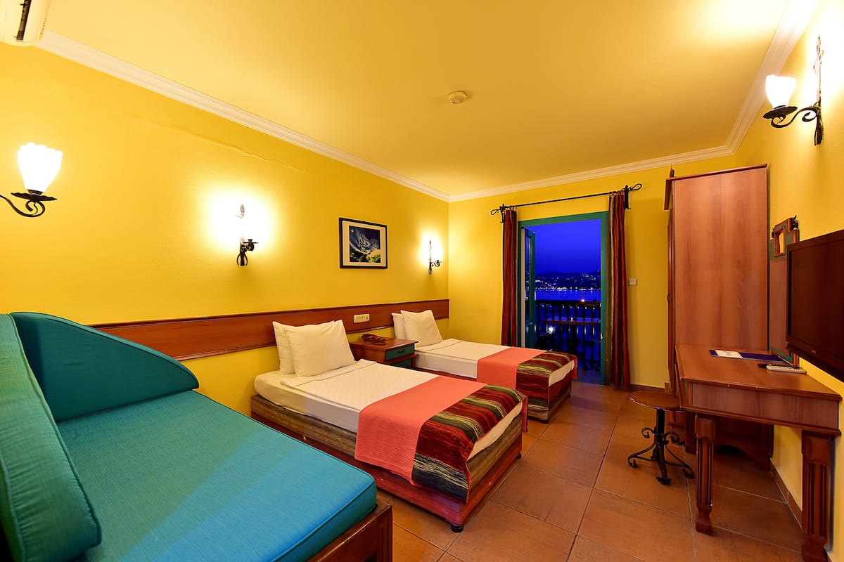 A hotel room with two beds, a desk, and a TV.