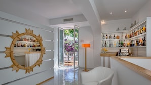Un hall d’hôtel moderne avec un bar, un grand miroir et une vue sur la terrasse extérieure.