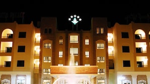 A hotel with a central fountain, multiple balconies, and a star-shaped light fixture above the entrance. - Hotel Gafsa Palace (Ksar)