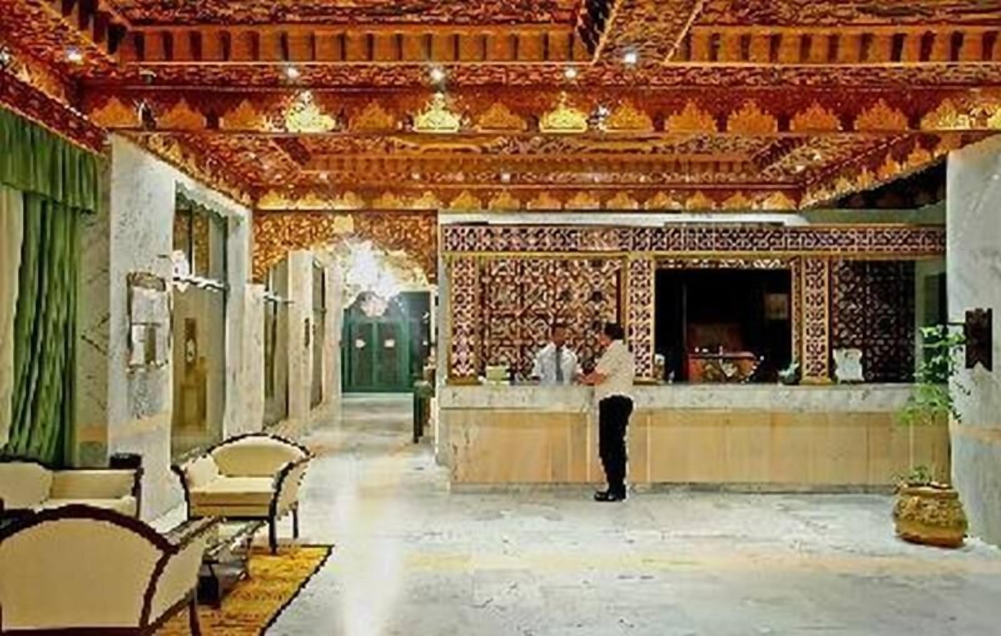 A lobby with a reception desk, chairs, and a decorative ceiling.