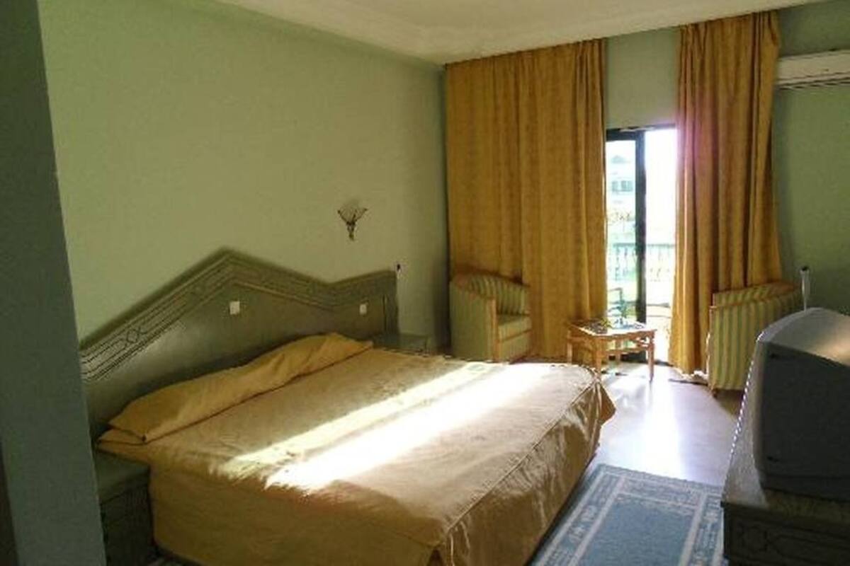 Ein Hotelzimmer mit Bett, Stuhl, kleinem Tisch und Heizkörper.