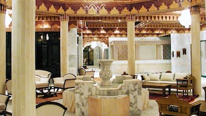 A luxurious lobby with ornate ceiling patterns, marble columns, and a central fountain. - Hotel Gafsa Palace (Ksar)