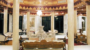 A luxurious interior with ornate columns, a central fountain, and marble furniture. - Hotel Gafsa Palace (Ksar)