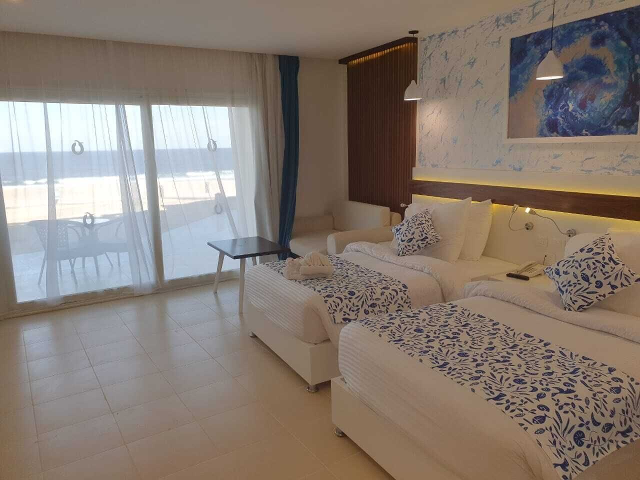 Een moderne hotelkamer met een groot bed, een bank, een kleine tafel en uitzicht door het raam.