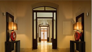 A hallway with a chandelier, two lamps, and a geometric floor pattern. - Hotel Termas - Balneario Termas Pallarés (Alhama de Aragon)
