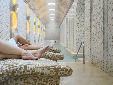 A spa area with tiled walls, a pool, and seating along the walls.