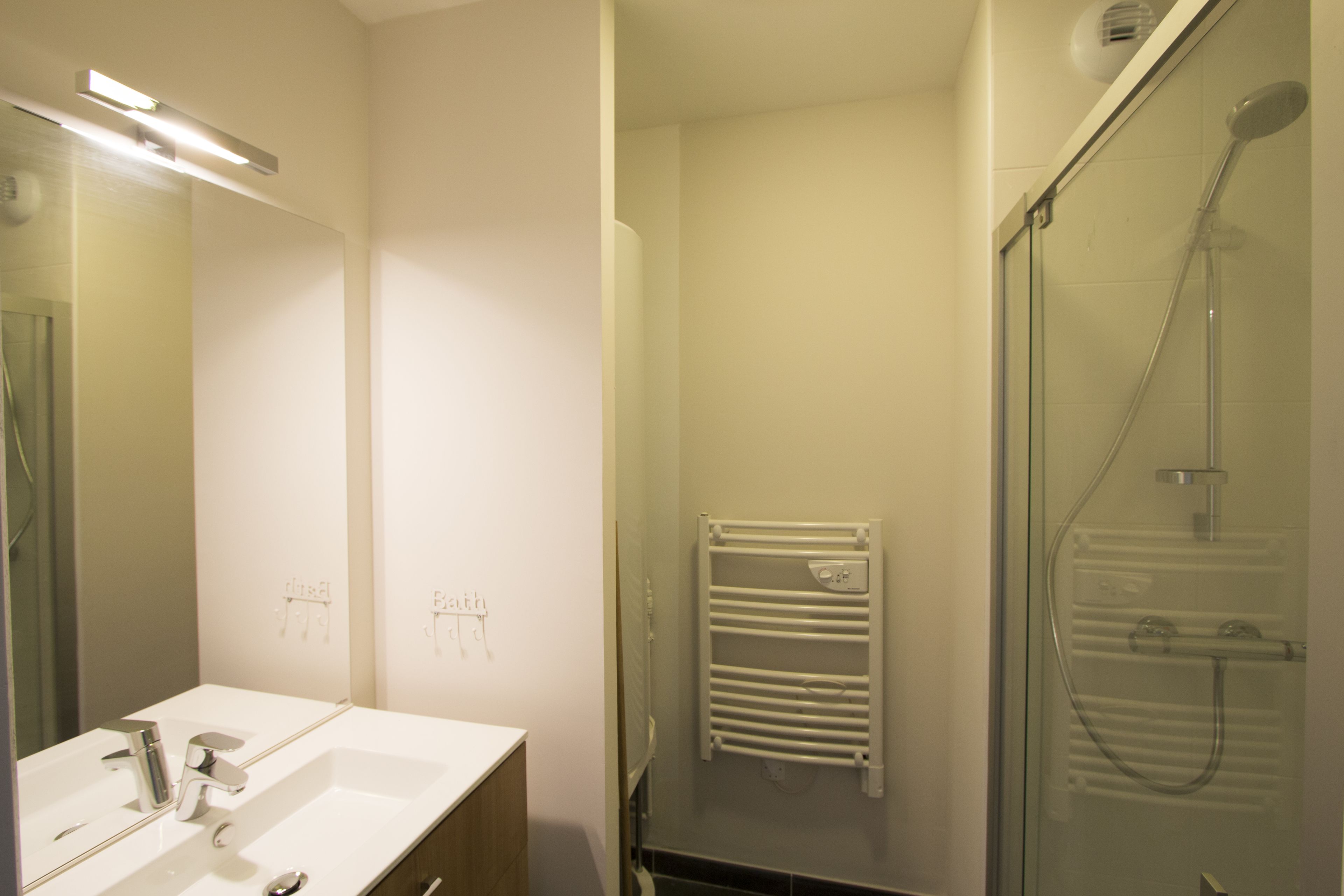 A bathroom with a white sink, mirror, and glass shower enclosure.