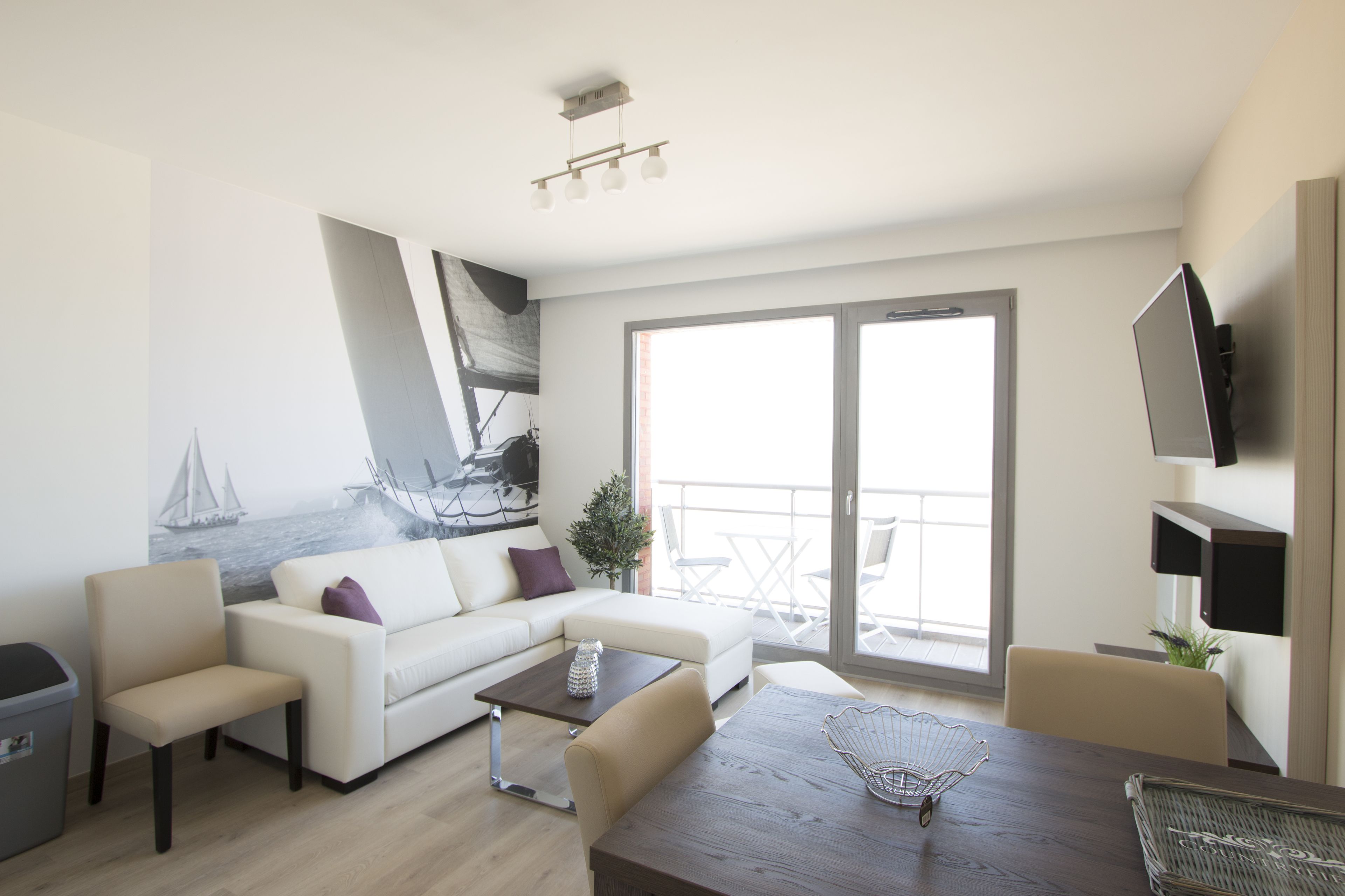 Un soggiorno moderno con un divano bianco, un tavolo da pranzo e un balcone vista mare.