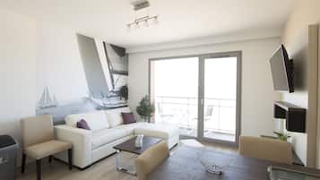 Un soggiorno moderno con un divano bianco, un tavolo da pranzo e un balcone vista mare.