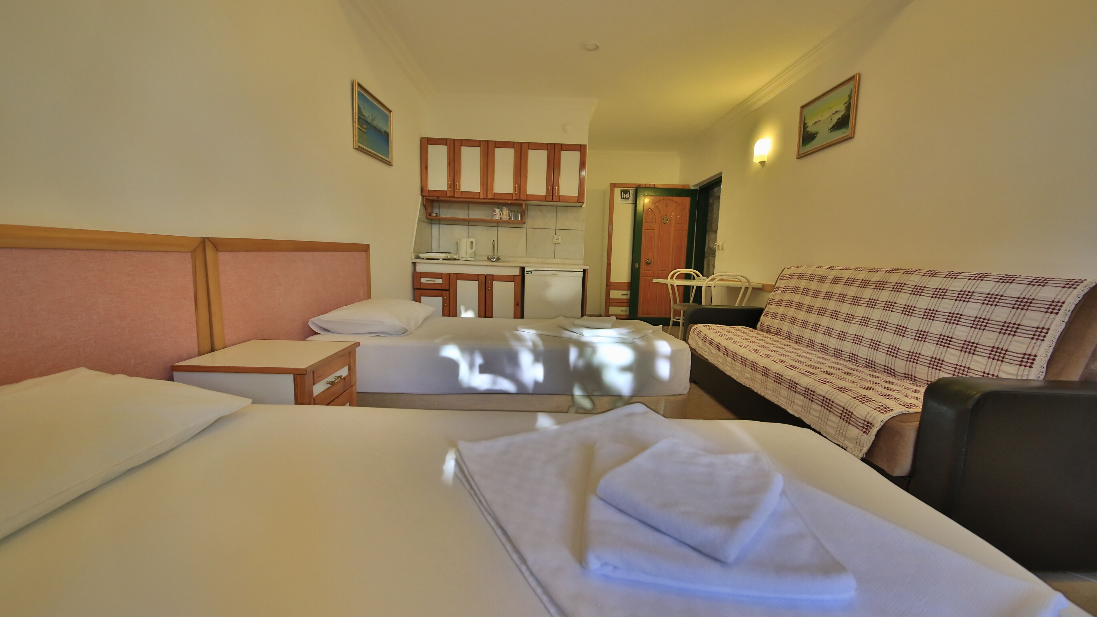 Una habitación de hotel con dos camas, un sofá, una kitchenette y un baño.