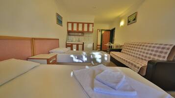 Una habitación de hotel con dos camas, un sofá, una kitchenette y un baño.