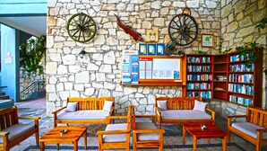 A lobby with stone walls, wooden furniture, a bookshelf, and informational posters. - Green House Apart Hotel (Bodrum)