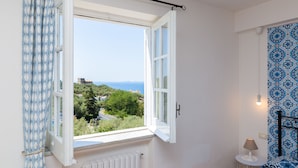 A room with a large window, a radiator, a small table with a lamp, and a patterned wall. - Villa Carolina Country House (Sorrento)