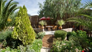 A garden patio with a wooden table, chairs, and a red umbrella. - Bahnhof Hotel Aus (Aus)