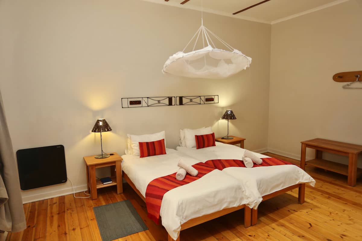 A bedroom with a bed, bedside tables, a hanging light fixture, and a wall-mounted artwork.