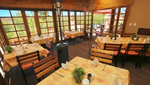 A restaurant with wooden tables and chairs, large windows, and a view of the outdoors. - Bahnhof Hotel Aus (Aus)