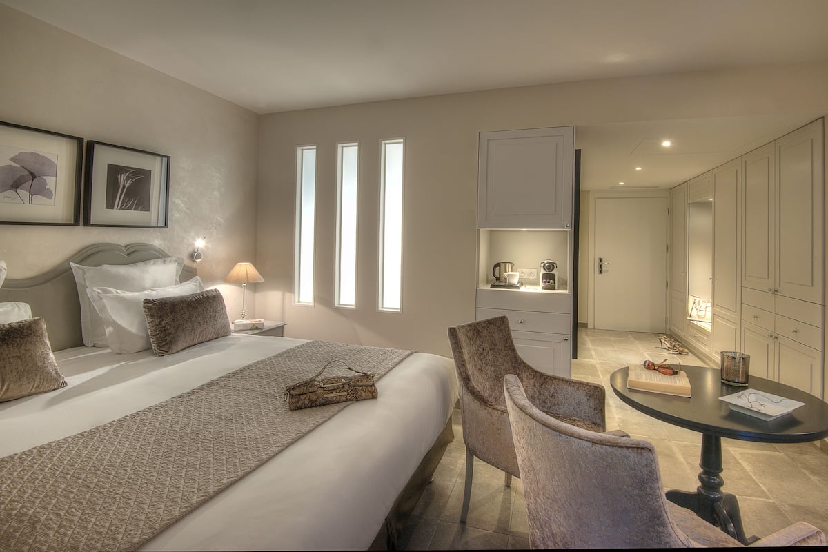 Et hotelværelse med en stor seng, et siddeområde med et bord og et tekøkken.