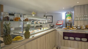 A breakfast bar with various food items, including fruits and condiments, and a coffee machine.