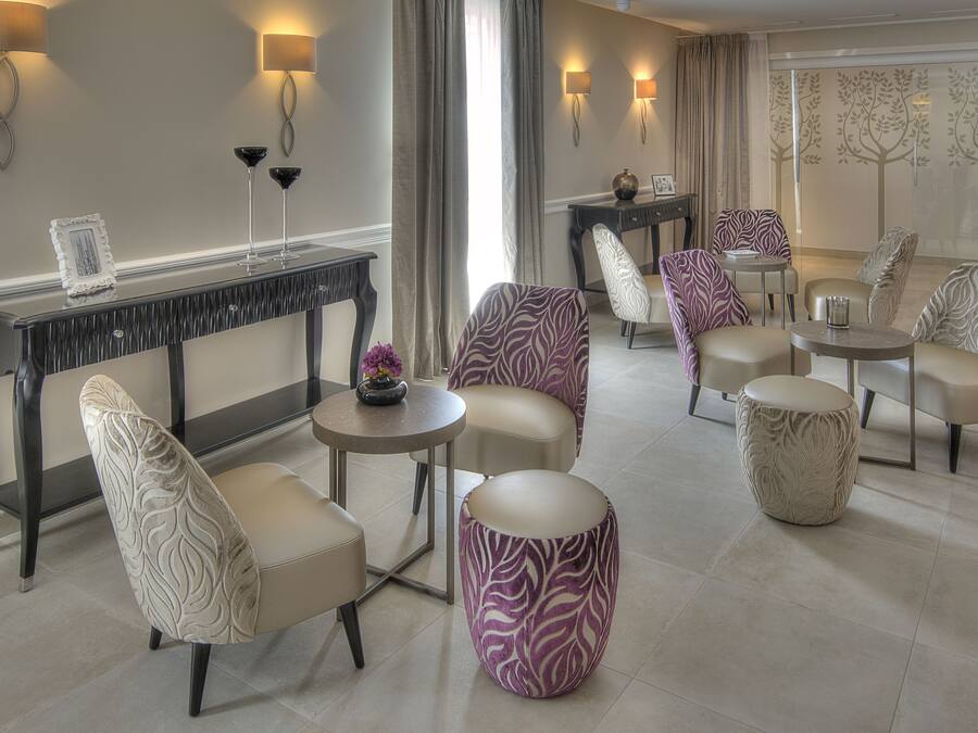 A modern lounge area with a console table, patterned chairs, ottomans, and ambient lighting.