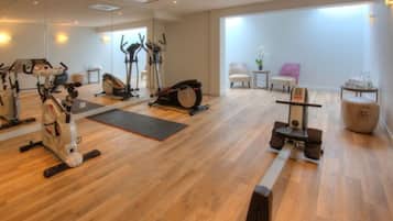 A spacious gym with various exercise equipment, a large mirror, and a view of the outside.