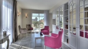 A modern living room with a large window, two chairs, a coffee table, and a built-in bookshelf.