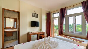 Habitació d'hotel amb llit, escriptori, televisió i balcó amb vistes.