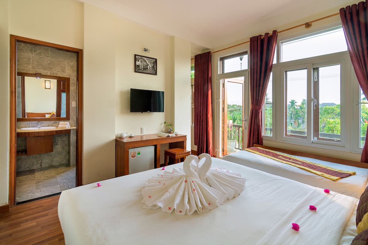 A hotel room with a bed, a desk, a television, and a balcony with a view.