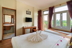 Ein Hotelzimmer mit Bett, Schreibtisch, Fernseher und einem Balkon mit Blick.