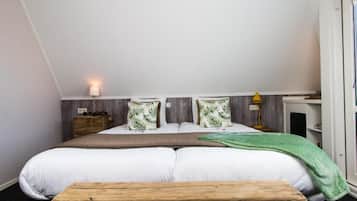 Et soveværelse med seng, puder, et sengebord, en lampe og en bænk.