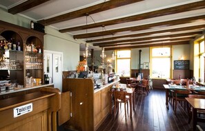 Una zona de bar con vigas de madera, barra y asientos.