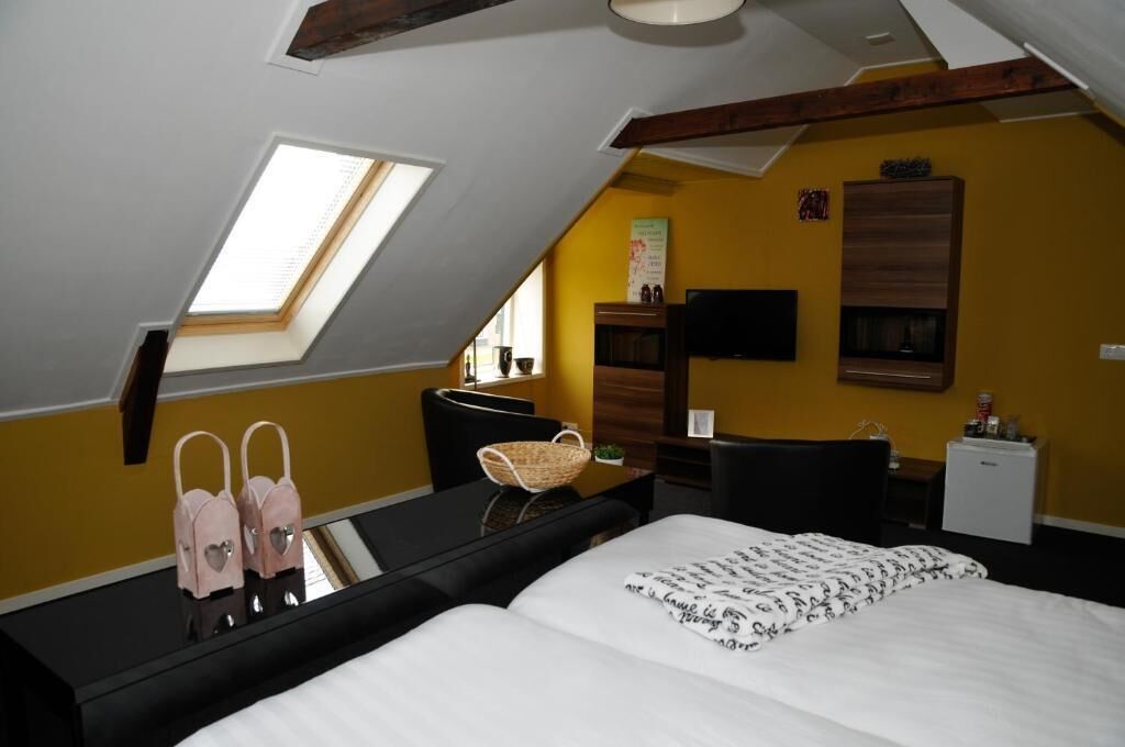 A bedroom with a skylight, a bed, a desk, and a small kitchenette.