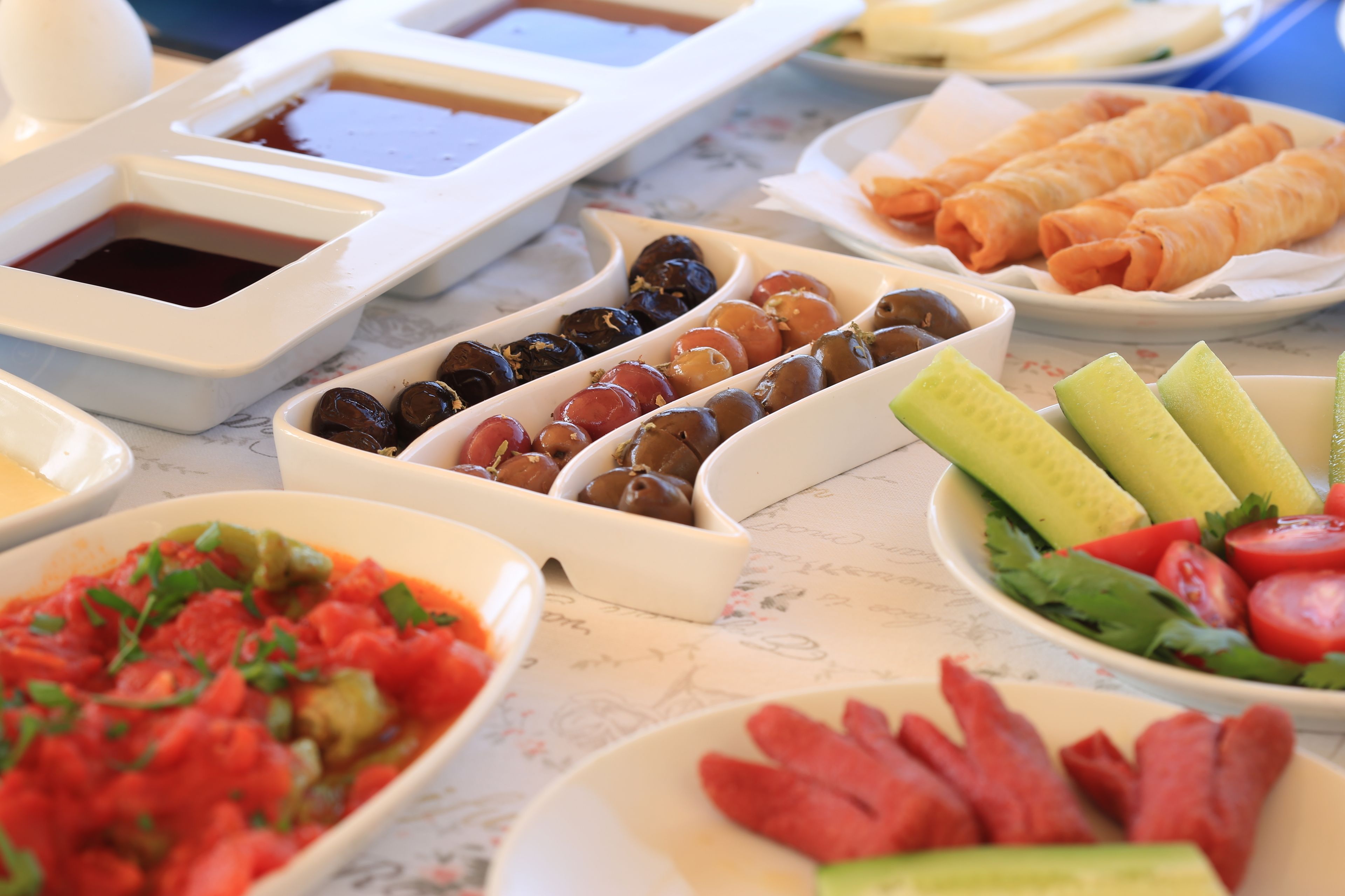 Ein Tisch mit verschiedenen Speisen, darunter Oliven, Brötchen und ein Salat.