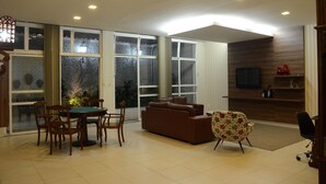 Amplia sala de estar con un sofá marrón, un sillón floral y una zona de comedor con mesa y sillas.