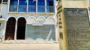 Un edificio de fachada blanca, con varios balcones y una estatua en su parte frontal.