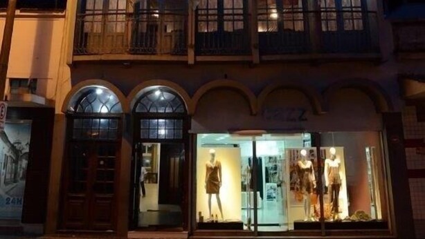 Un edificio de varios pisos con balcones, una tienda en la planta baja con maniquíes y una farola.