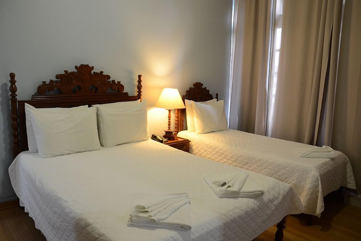 A double bed with a wooden headboard, two bedside tables with lamps, and neatly folded towels on the bed.