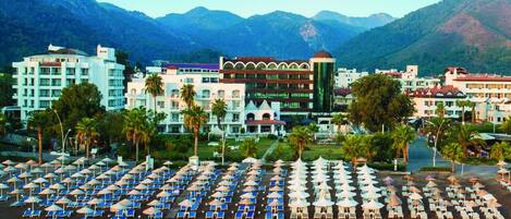 A resort with a large pool area, multiple buildings, and a mountainous backdrop.