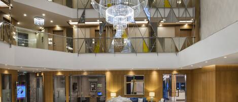 A multi-level atrium with a central water feature, glass railings, and modern lighting fixtures.