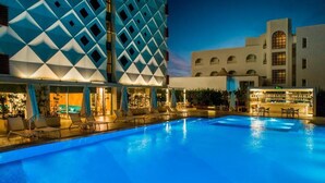 A swimming pool with lounge chairs and a bar area, surrounded by buildings with geometric patterns and arched windows. - Elite World Marmaris - Adult Only (Marmaris)