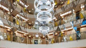 A multi-level hotel lobby with a central water feature, glass railings, and modern lighting. - Elite World Marmaris - Adult Only (Marmaris)