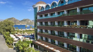 A modern hotel with multiple floors, large windows, and a view of the sea. - Elite World Marmaris - Adult Only (Marmaris)