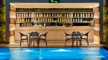 A bar area with a poolside seating arrangement, a bar counter with various bottles, and a sign above indicating 'The Palm Bar'.