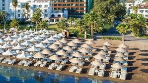 A hotel with a pool area, beach umbrellas, and palm trees. - Elite World Marmaris - Adult Only (Marmaris)