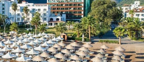 Un hôtel doté d’une piscine, de parasols de plage et de palmiers.