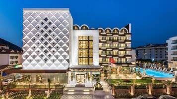 Un hôtel moderne à la façade géométrique, doté d’un espace piscine et d’une entrée bien éclairée.