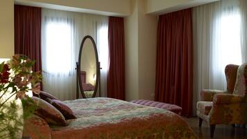 A bedroom with a large bed, a chair, and a mirror.