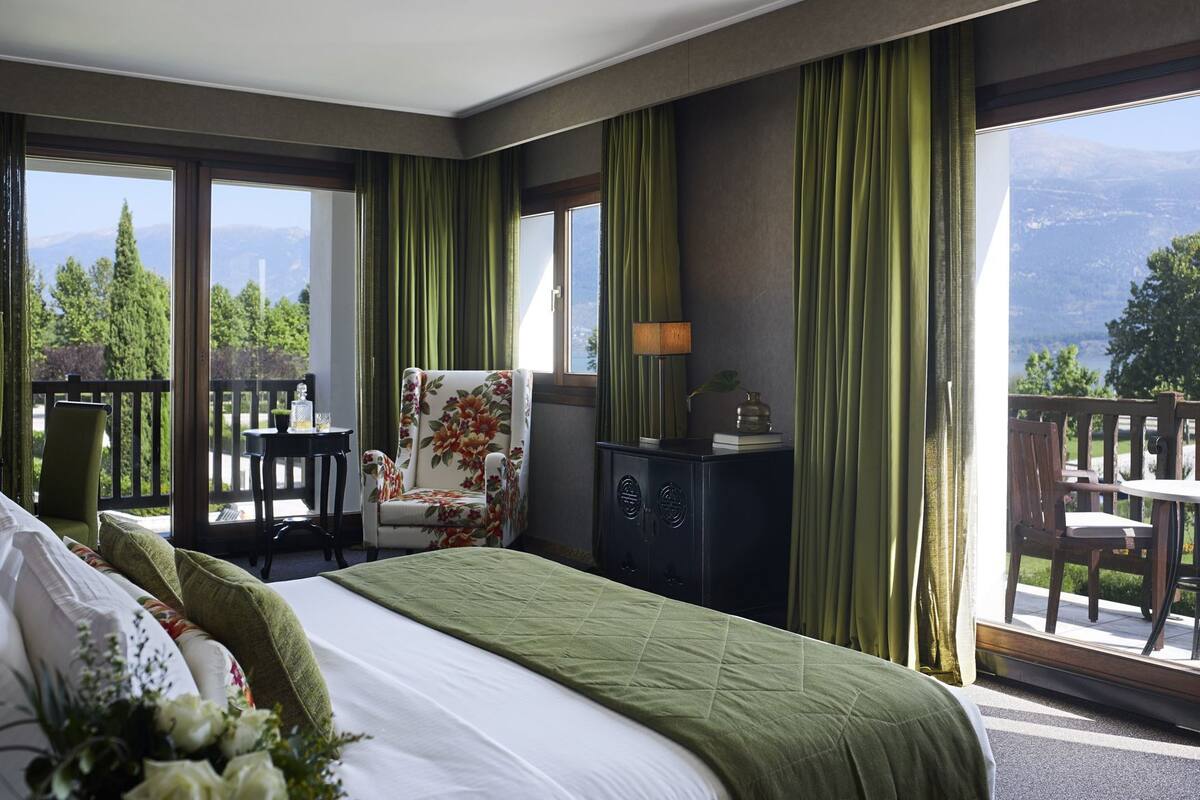 A hotel room with a bed, a chair, a desk, and a view of the outdoors.