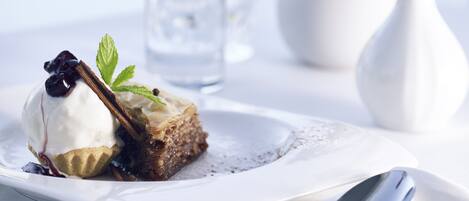 A dessert with a scoop of ice cream, a piece of cake, and a mint leaf on a white plate.